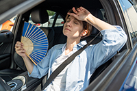 Exhausted middle aged woman drives car waves blue fan suffers from stuffiness in traffic jam.